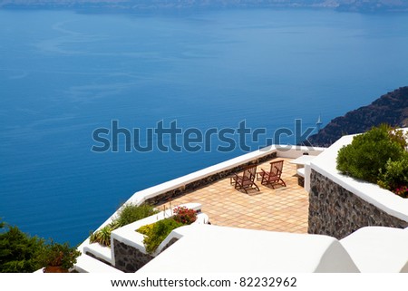 A tranquil scene of deck chairs on a terrace overlooking the mediterranean sea in Thira, Santorini, Greece