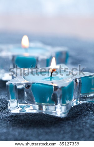 Close-up of blue candles in star shape holders on silver sand