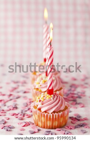 Close-up of pink muffins with party candles. Studio shot.