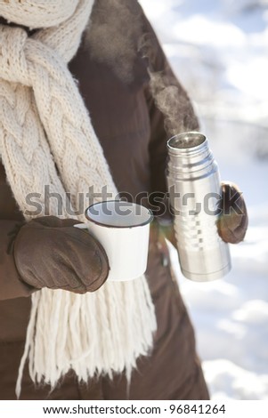 Mug and thermos of hot chocolate on a cold winter day