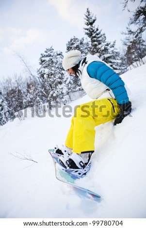 Female snowboarder sitting in snow with snowboard in beautiful cold winter weather