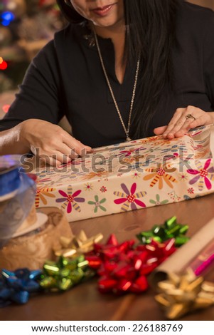 woman wrapping gifts / looks like they are for christmas / judging by decor