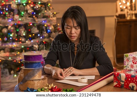 woman writing cards / looks like they are for christmas / judging by decor