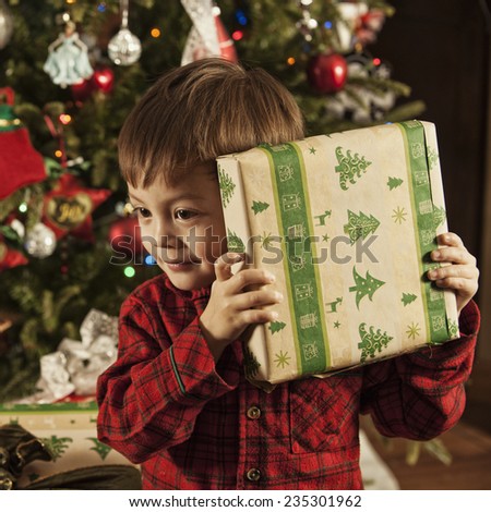 well hold on; what\'s this? / little boy checking a gift / to see what\'s inside