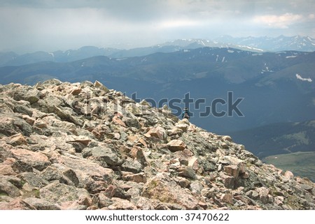 Mountain Summit Woman Hiking Summer Rain Storm. Colorado Summer Mountain Backcountry Scene. Great for themes of nature, summer, mountains, outdoor recreation, travel destinations, background scenic.