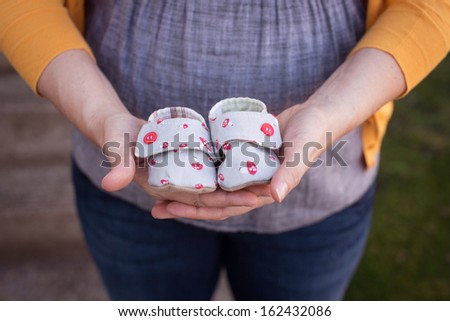 Expectant mother holding baby shoes