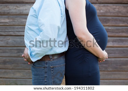 Pregnant couple standing back to back