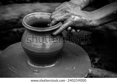 Black and white striking image of a potter\'s hands shaping soft clay to make an earthen pot