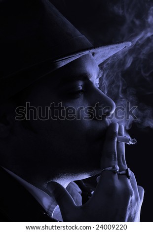 portrait of a man in black and white immensely enjoying the last puff from his cigarette in the light of the night