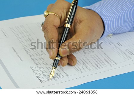 hand of a man filling an application form wearing formal shirt and using expensive fountain pen