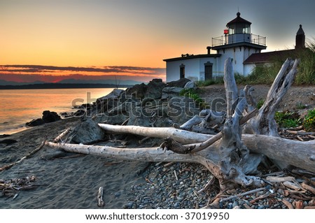 West Point lighthouse at Discovery park Seattle at dusk with drift wood in the foreground