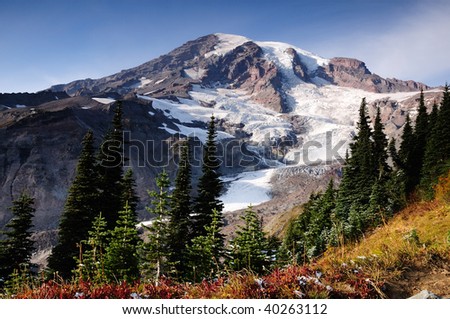 Nisqually glacier at Mount Rainier park. first snow of the season in the foreground amidst fall colors