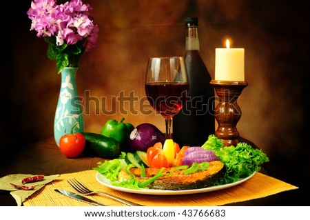 Still life of delicious dish of fish with salad and served with vintage red wine