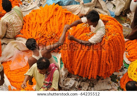 CALCUTTA - OCTOBER 14: An unidentified flower seller buys marigold garlands from a wholesaler on October 14, 2010 in Calcutta, India. The garlands are in very high demand during Diwali festival.