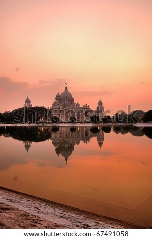 Victoria memorial, the iconic British architecture in India during colonial rule, reflected across a lake at sunset.