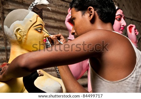 CALCUTTA - AUGUST 14: An artisan draws the eyes of goddesses on August 14, 2011 in Kumartuli, Calcutta, India. These idols are made for the bengali festival of Durga Puja also known as Dassera.