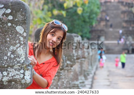 Cute woman in orange clothes stand behind stone post at Phanomrung temple, Thailand