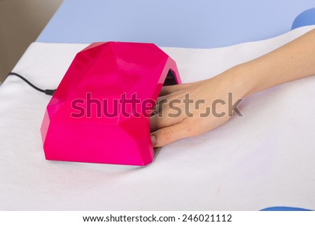 step of manicure process: nail gel polish drying in manicure lamp