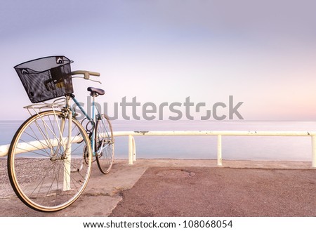 Old and vintage bicycle at the railing near the sea. Blue sea and sunset sky in background. A lot of copy space. Nice, France, Europe.