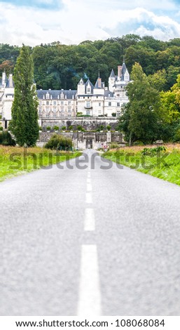 View of beautiful old french castle Chateau d\'Usse. Road in foreground leading to the castle and blue cloudy sky in background.