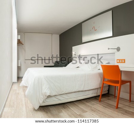 Beautiful stylish interior in modern style. Elegant design of furniture. Clean empty hotel room with double bed. Contrast of pastel colors and bright details. Night with closed window and light on.