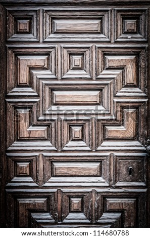 Closed old solid door with wood texture and carved geometric ornament. Dark vintage and antique style. Great for background.