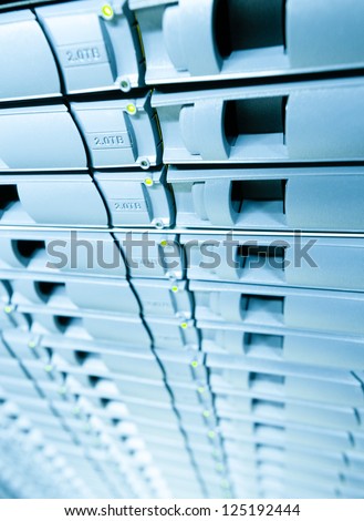 Row of hard drives mounted in rack in data center. Storage area with disks. Modern computer technology. Abstract blue background. Network room with server and hardware for communication and internet.