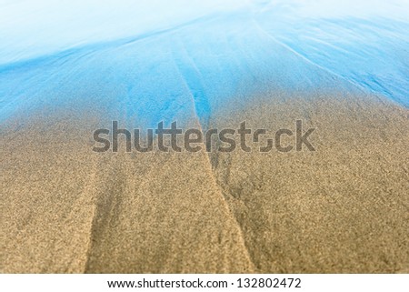 Blue waves on beautiful sandy beach. Ripple on surface of sea. Seabed through transparent water at coastline. Swimming in crystal clear water. Popular outdoor activity. Concept of summer vacations.