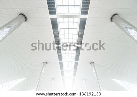 Vanishing roof of airport. Metal columns and white ceiling with glass windows. Symmetric architecture. Transparent roof of high building. Minimalistic design of construction. Public tourist place.