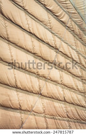 Rumpled sewed-in sail of light brown color. Vietnamese boat sail in close up view. Abstract backgrounds and wallpapers. Materials, textiles and fabric texture.