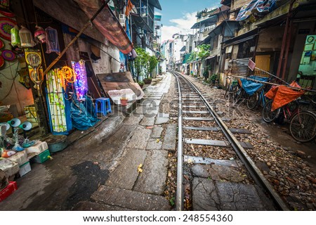 Perspective view of railway running along narrow street with houses in Hanoi, Vietnam. Unusual solution of transport problem. Dangerous neighborhood for people. Travelling and tourism.