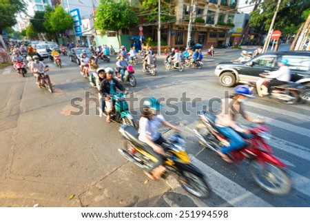 Motion view of street in Vietnam. Southeast Asia. Busy daily traffic with stream of motorbikes and cars. Blurry view of bikes in foreground. Transportation and traffic.
