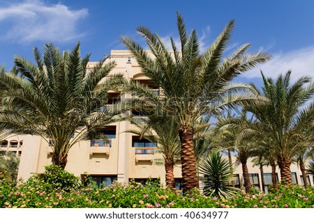 hotel building with blue cloudy sky in background and palm trees in foreground