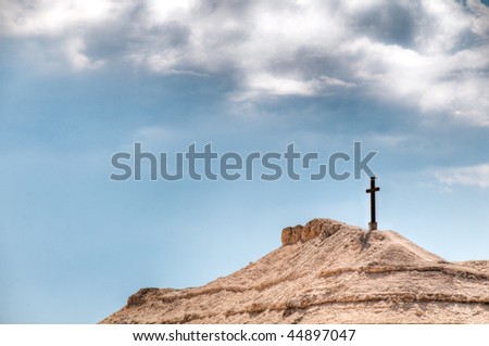 cross on the mountain with blue cloudy sky in background