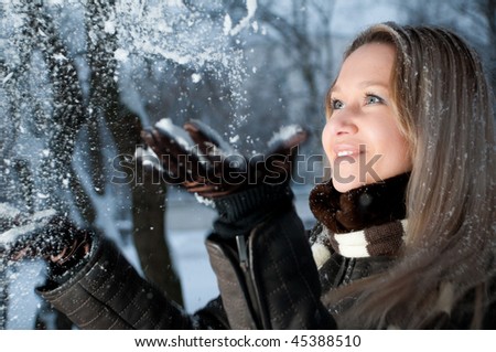 portrait of beautiful happy young woman throwing snow up with her hands