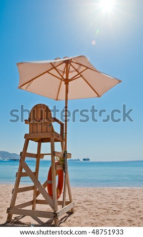 beach security chair on the sand near the sea line with bright sun and blue sky in background