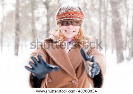winter street portrait of young beautiful natural looking woman smiling and playing hide and seek with hat closing her eyes