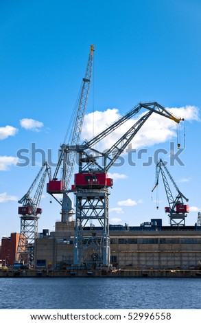 sea port cranes with blue cloudy sky in background and water in foreground in Helsinki port, Finland