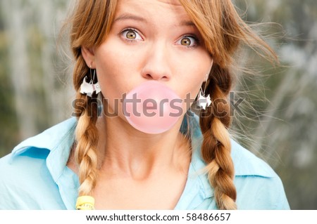beautiful young student girl blowing bubble from chewing gum and looking into the camera