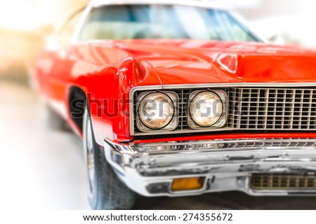 Close Up Detail of Shiny Red Classic Car with Focus on Headlights and Hood.