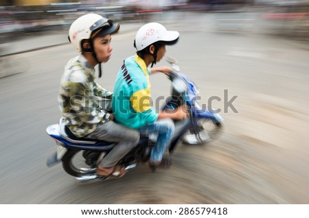 HOI AN, VIETNAM - DECEMBER 4: Two men in helmets riding bike. The most popular means of transport in this country. 4th place in bike usage in world. December 4, 2012, Hoi An, Vietnam, Asia.
