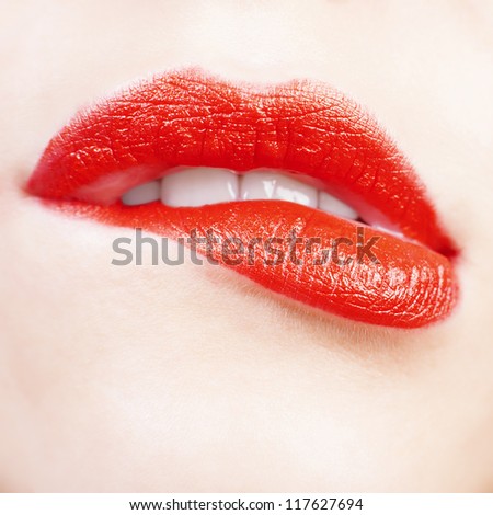 Young woman bit her lower lip.Lips closeup. Red color