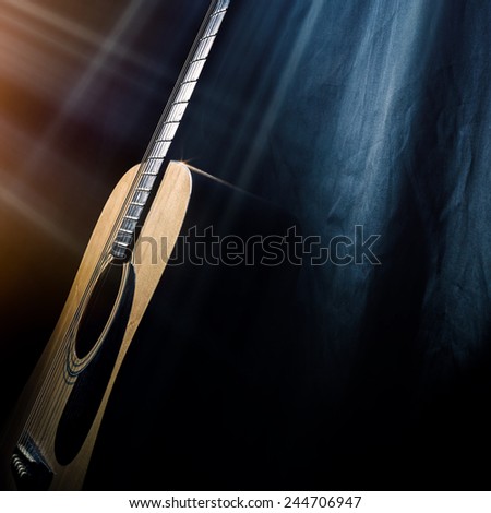 acoustic guitar on a black background in the rays of light