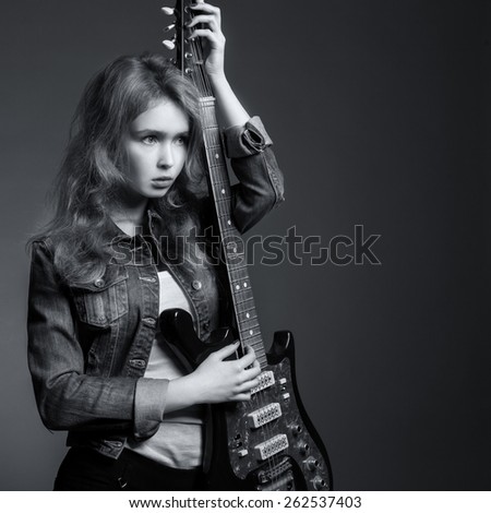 girl in a denim jacket with an electric guitar in his hands