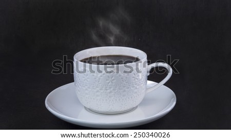 Lace cup of coffee with steam on dark background