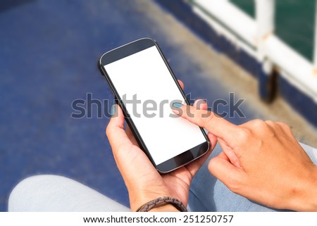 Female hand holding and using smart phone mock up and touching white blank screen with copy space.