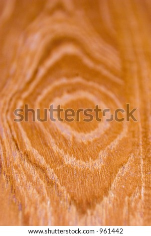 Wood grain shot at an angle, focus at front of the knot in the wood.