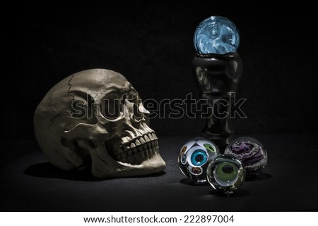 Dark and shadowy human skull in a pool of light. Crystal balls with eyeballs looking out