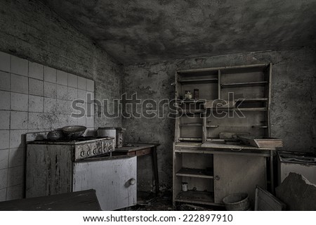 A dark, shabby kitchen in a dilapidated, abandoned house.