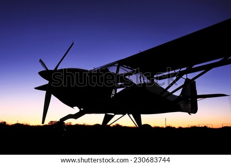 A silhouette of a small bush plane at sunset